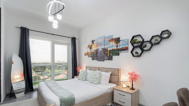 Ein Schlafzimmer mit Bett, Nachttischen, einem Fenster mit Vorhängen, Blick auf die Stadt und Kunstwerken an der Wand.