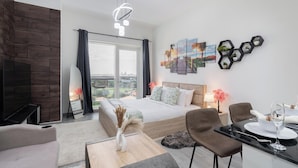 Ein modernes Hotelzimmer mit einem großen Bett, einem Schreibtisch mit Stuhl, einem Fernseher und Blick auf die Stadt.