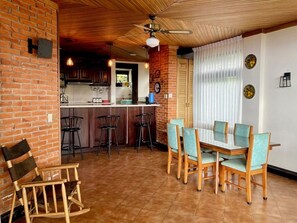 Un espace repas avec un mur en briques, un plafond en bois et une cuisine en arrière-plan.