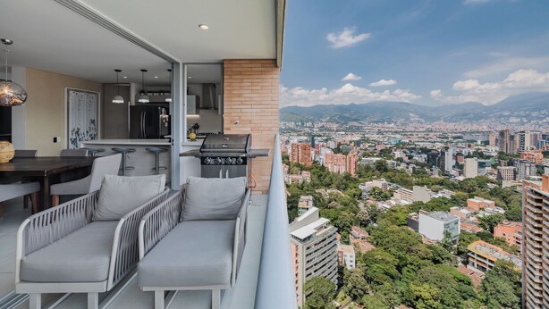 Un balcon avec un coin repas, une cuisine et une vue sur la ville.