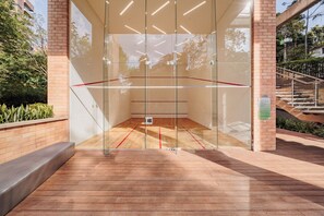 A squash court with glass walls, wooden flooring, and a staircase outside. -  Luxury Apartment with Panoramic Views in Provenza (Medellín)
