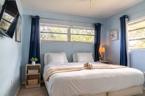 Ein Schlafzimmer mit einem Bett, einem Nachttisch, einer Lampe, einer Stern-Dekoration und einem Fenster mit Vorhängen.