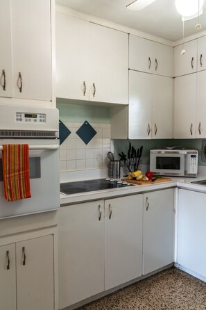 A kitchen with white cabinets, a microwave, a stove, and a sink. - Private Coastal Haven: Fire Pit • Yard • Beach (Sarasota)