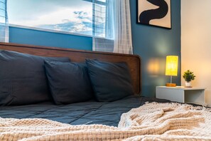 A bedroom with a bed, a bedside table with a lamp, and a window with curtains. - Chic Local Hideaway: BBQ Nights • Near Beach (Sarasota)