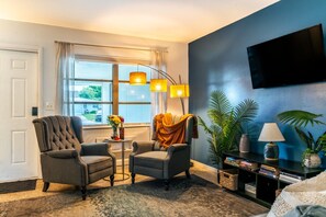 A living room with a sofa, armchairs, a coffee table, a TV, and a bookshelf. - Chic Local Hideaway: BBQ Nights • Near Beach (Sarasota)
