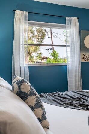A room with a bed, a window with sheer curtains, and a view of greenery outside. - Chic Local Hideaway: BBQ Nights • Near Beach (Sarasota)