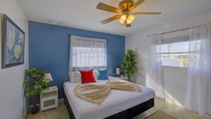 A bedroom with a bed, a ceiling fan, a window with curtains, a nightstand, and a potted plant. - Chic Local Hideaway: Yard |BBQ Nights | Near Beach (Sarasota)
