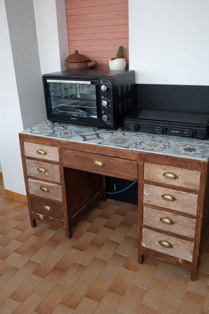 Una kitchenette con microondas, tostadora y un pequeño cactus en la encimera.