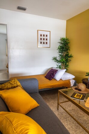 Ein stilvolles Wohnzimmer mit einer Couch, einem kleinen Couchtisch und einer Pflanze.