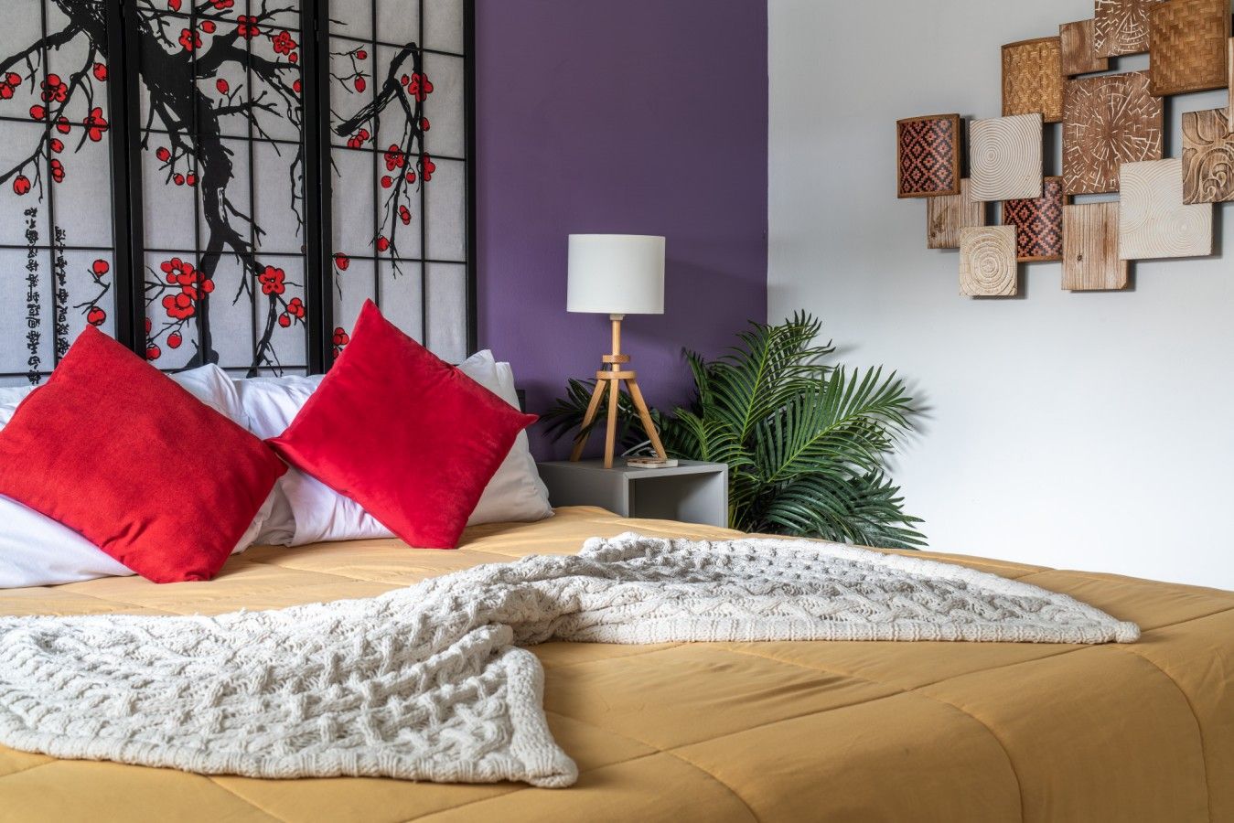 A bedroom with a bed, pillows, a lamp, and wall art.