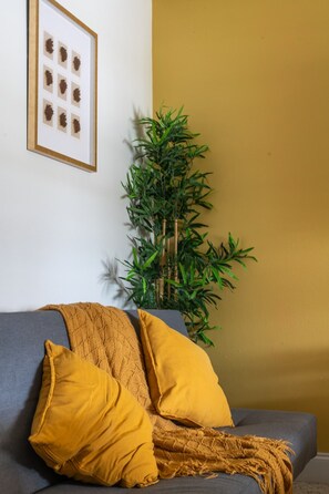 A room with a sofa, a framed picture, and a plant. - Chic Sarasota Gem: Beach • BBQ • Workspace • Patio (Sarasota)