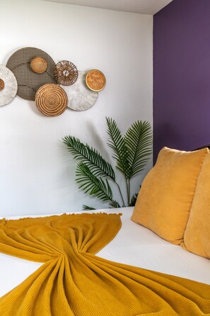Ein Zimmer mit einem Bett, einer Wanddekoration und einer Pflanze.