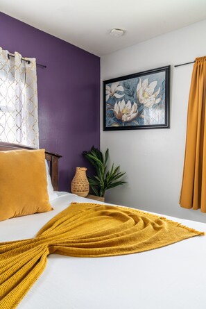 A bedroom with a bed, a painting, a plant, and a vase. - Chic Sarasota Gem: Beach • BBQ • Workspace • Patio (Sarasota)