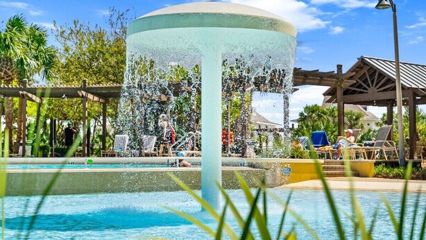 Ein Schwimmbecken mit einer Springbrunnen, Liegestühlen und einem Pavillon.