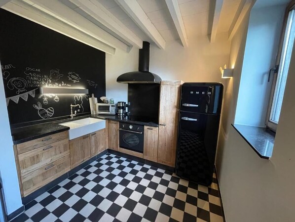 Una cocina con una pizarra, una estufa, un fregadero y un refrigerador.