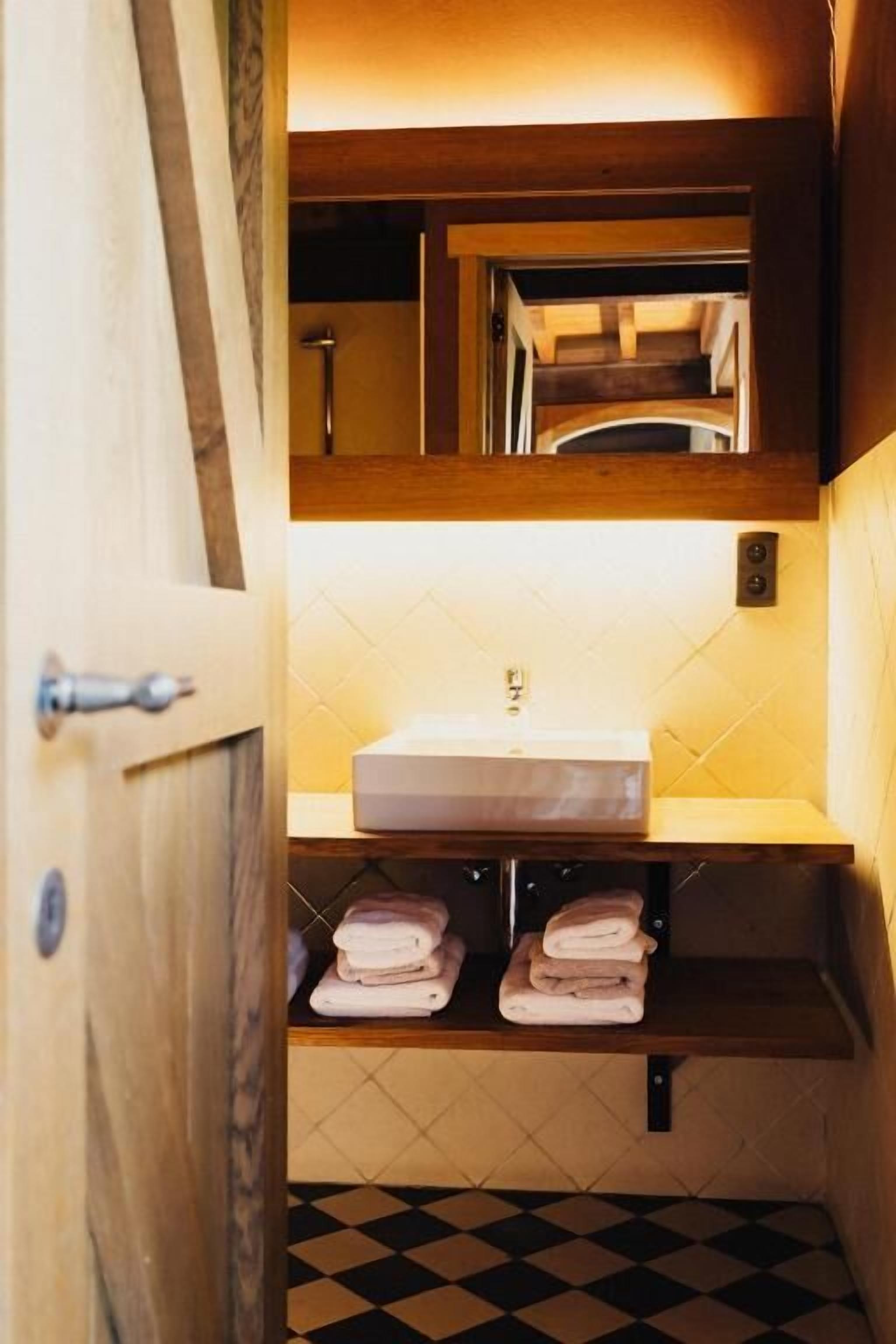 Un bagno con un mobile bagno in legno, un lavandino e un pavimento a scacchi.