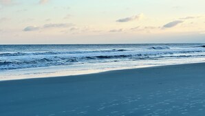 En strand med vågor, en klar himmel och en kustlinje som sträcker sig långt bort.