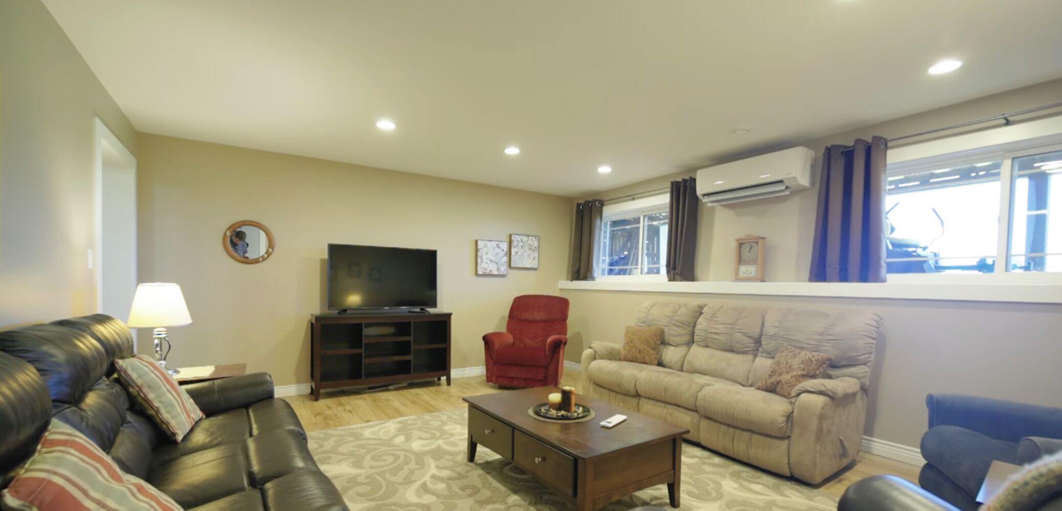 A living room with a sofa, a red armchair, a television, and a coffee table.