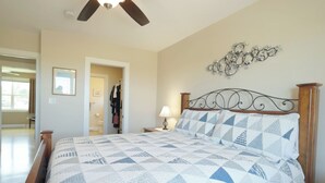 A bedroom with a bed, dresser, ceiling fan, and a door leading to another room. - Coastal 4BR Getaway w/ Water Views, 2 Min to Brackley Beach (Brackley Beach)