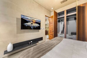 A modern bedroom with a large bed, a TV mounted on the wall, a wooden wardrobe, and a small shelf with decorative items. - South Lake Tahoe 2 Bedroom 2 Bath (South Lake Tahoe)