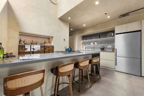 A modern kitchen with a central island, bar stools, stainless steel appliances, and a clock on the wall. - Paradise South Lake Tahoe 3 Bedroom 3 Bath (South Lake Tahoe)