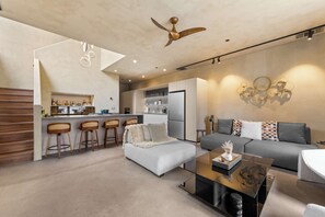 A modern living space with a sofa, ottoman, and a coffee table. There is a kitchen area with a refrigerator and bar stools. - Paradise South Lake Tahoe 3 Bedroom 3 Bath (South Lake Tahoe)