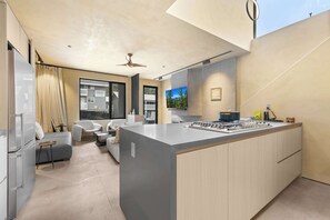 Eine moderne Küche mit einer großen Kochinsel, ein Essbereich mit einer Couch und Stühlen sowie ein Blick auf eine Berglandschaft durch ein Fenster.