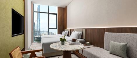 Una habitación de hotel moderna con cama, sofá y una mesa redonda con una planta.