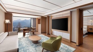 A modern hotel room with a large TV, a sofa, a dining table, and a view of mountains. - Days Hotel By Wyndham Lishui Liandu (Lishui)