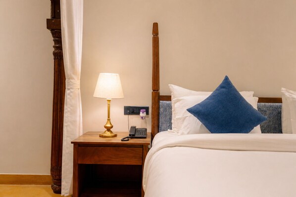 A hotel room with a bed, a nightstand with a lamp, a telephone, and a blue pillow. - HOTEL AUREA JAISALMER (Jaisalmer)
