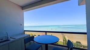 A balcony with a view of the sea, a round table, and a sink.