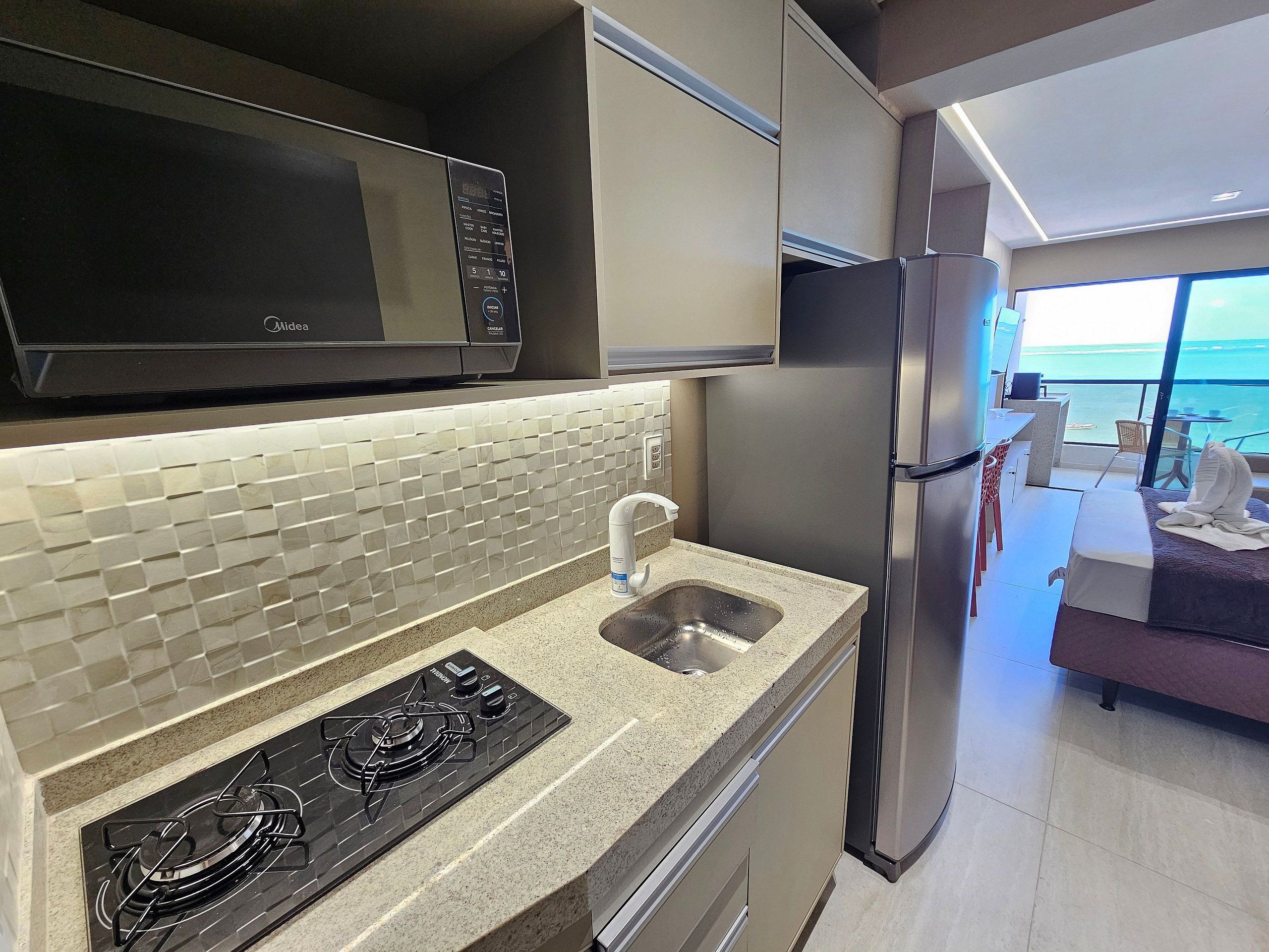 A modern kitchen with a gas stove, microwave, and stainless steel refrigerator.