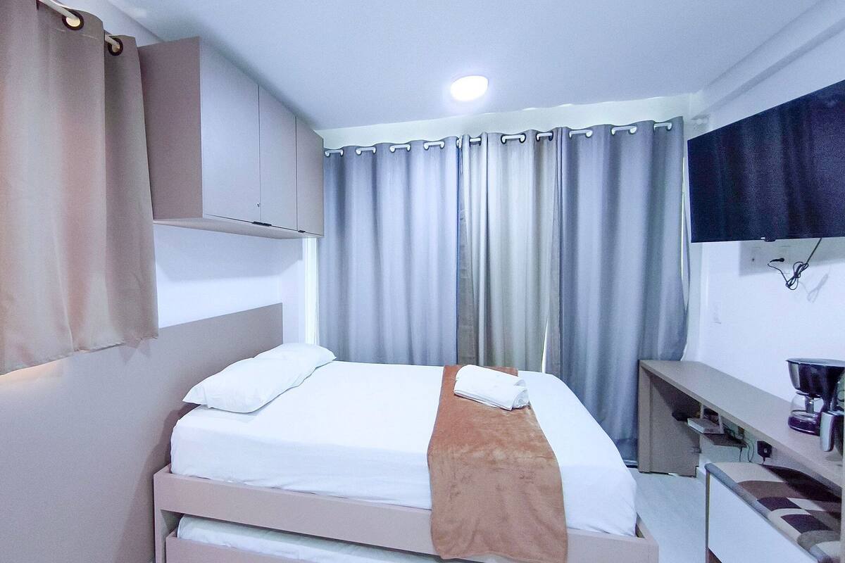 A hotel room with a bed, a desk, and a television.