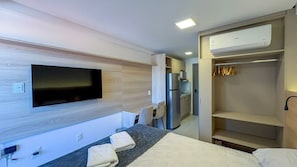 A hotel room with a bed, a desk with a flat-screen TV, a kitchenette, and a walk-in closet. - Prime Beach Tamandaré (Tamandaré)