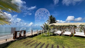 A beachside view with a wooden fence, lounge chairs, and a clear sky. - Prime Beach Tamandaré (Tamandaré)