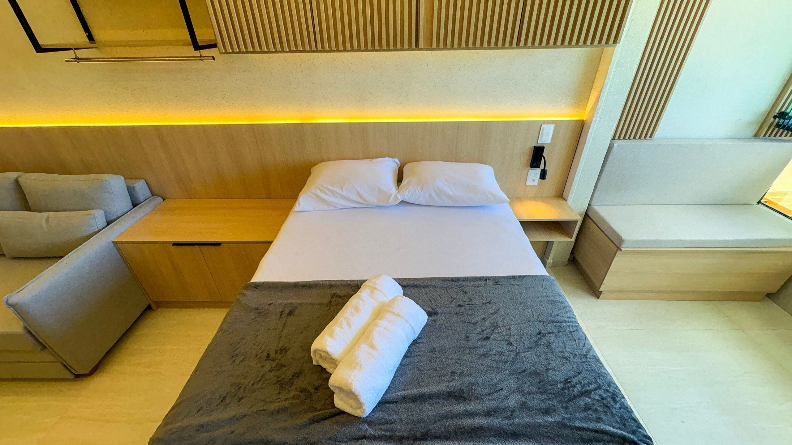 Una habitación de hotel con cama, sofá, una mesita y una mesita de noche.