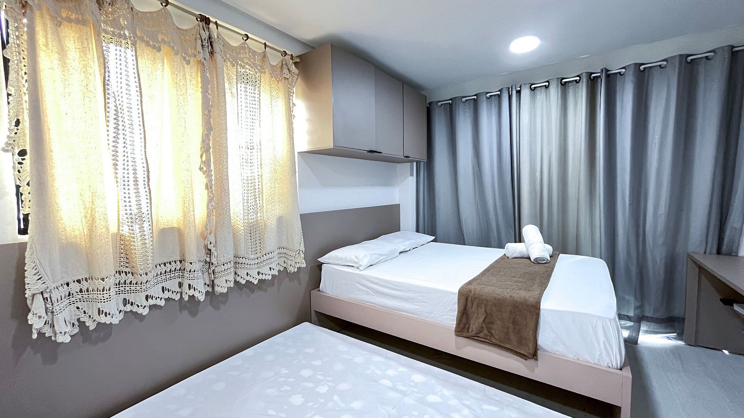 A hotel room with a bed, a bedside table, a lamp, and curtains.
