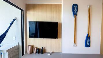 A room with a mounted flat-screen TV, two blue paddles, and a wooden door.