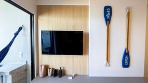 A room with a mounted flat-screen TV, two blue paddles, and a wooden door. - Prime Beach Tamandaré (Tamandaré)