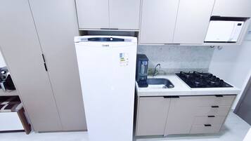 A compact kitchen with a white refrigerator, a gas stove, and a sink.