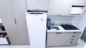 A compact kitchen with a white refrigerator, a gas stove, and a sink. - Prime Beach Tamandaré (Tamandaré)