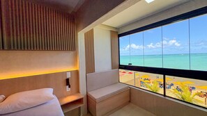 A hotel room with a large window offering a view of the beach and ocean. - Prime Beach Tamandaré (Tamandaré)