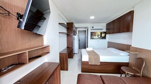 A modern hotel room with a bed, wooden furniture, a TV mounted on the wall, and a painting on the wall. - Prime Beach Tamandaré (Tamandaré)