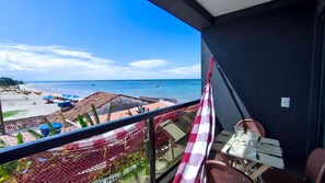 A balcony with a view of the beach, a table with chairs, and a hammock. - Prime Beach Tamandaré (Tamandaré)