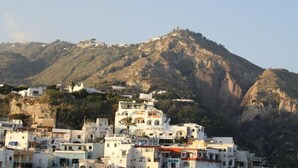 A coastal town with buildings on a hillside, overlooking a mountainous backdrop.