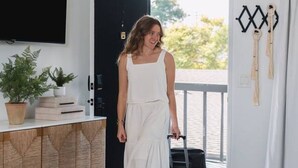 Een kamer met een televisie, een kamerplant, een houten kast, een rieten stoel en een deur naar buiten.