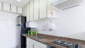 A kitchen with a gas stove, stainless steel refrigerator, and white cabinets. - Fully furnished apartment near Higienópolis Shopping Mall. (São Paulo)
