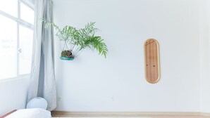 A bedroom with a bed, a window with curtains, a potted plant, and a wooden wall decoration. - Fully furnished apartment near Higienópolis Shopping Mall. (São Paulo)