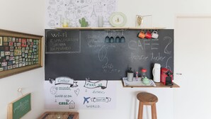 A room with a chalkboard displaying various doodles and text, a framed photo collage, and a small shelf with mugs and a kettle. - Fully furnished apartment near Higienópolis Shopping Mall. (São Paulo)