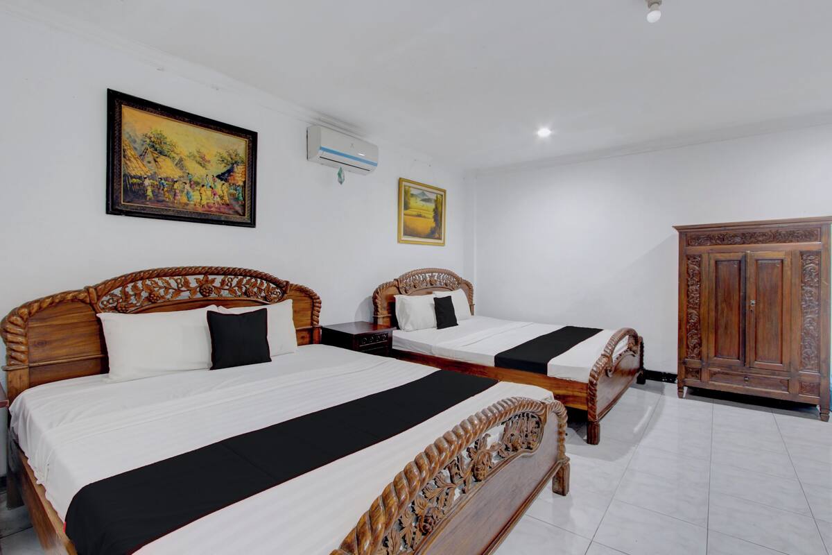A hotel room with two wooden beds, a wardrobe, and a painting on the wall.
